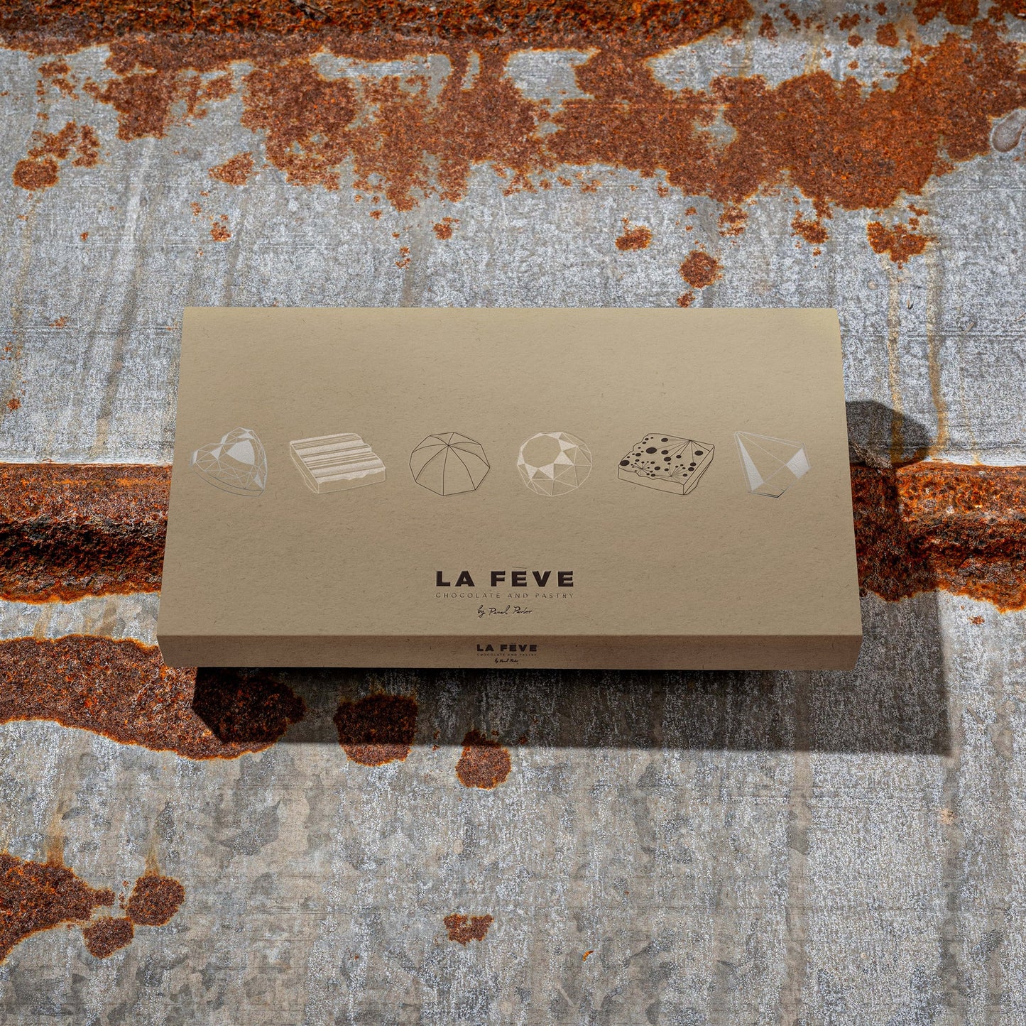 La Feve's eco-friendly kraft chocolate packaging on a rusted metal surface