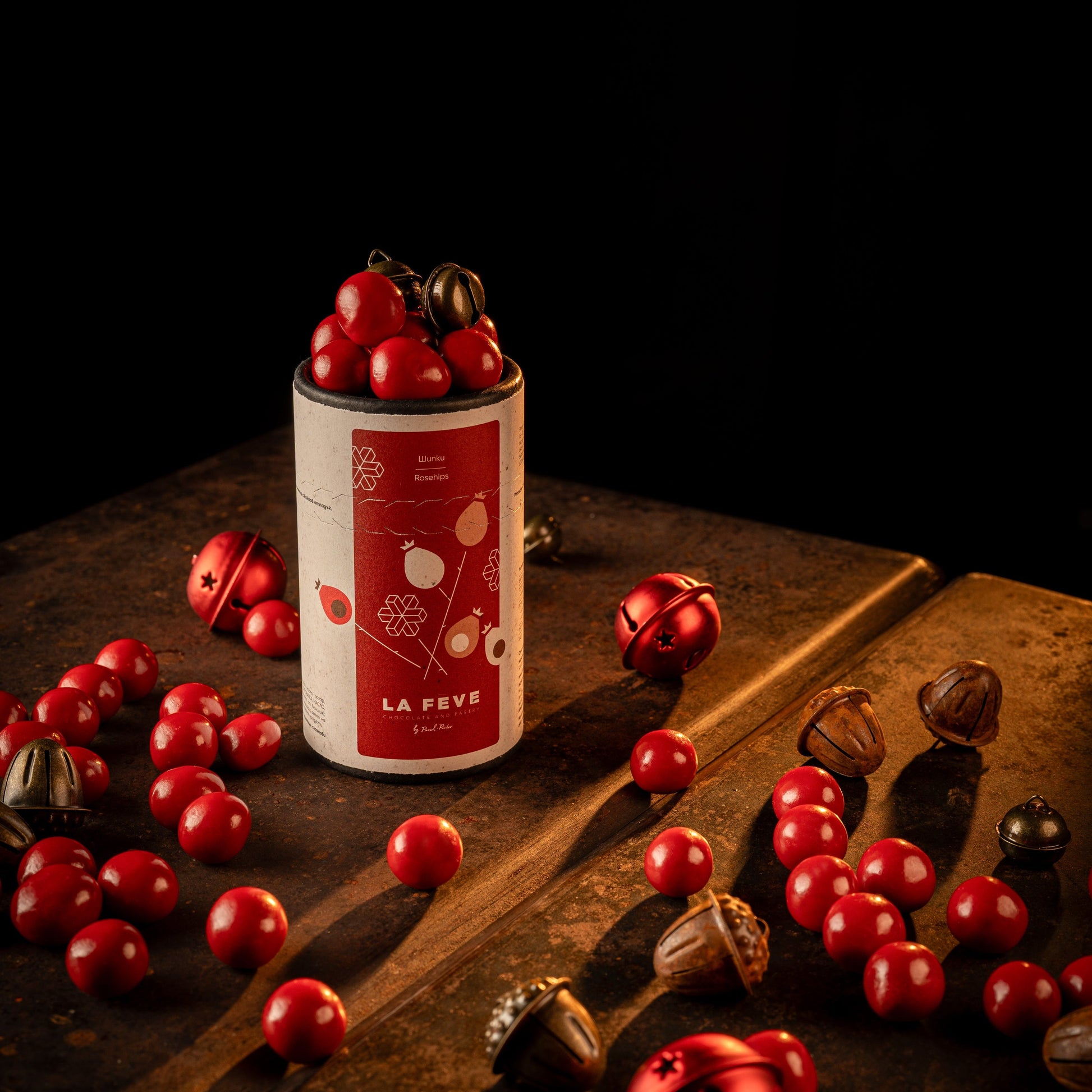 a tube packaging labeled 'La Fève' with red rosehip fruits on a dark surface