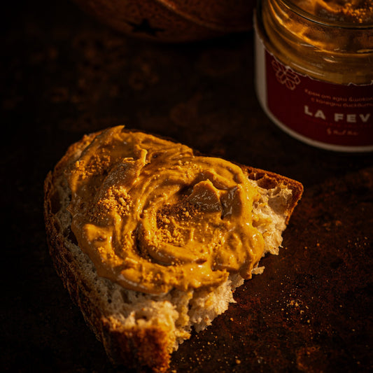 Bread wihth nutty spread and a jar labeled 'La Feve' on a dark background