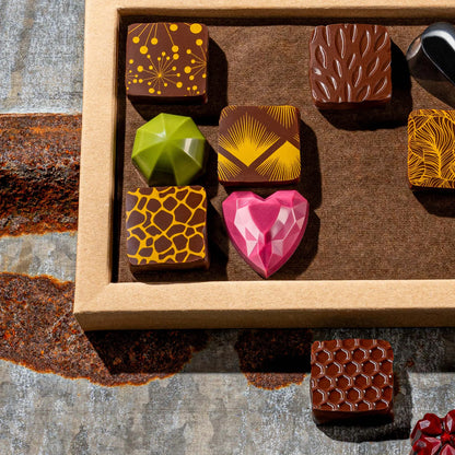 Gemstone like assorted chocolate pieces in a box on a textured surface