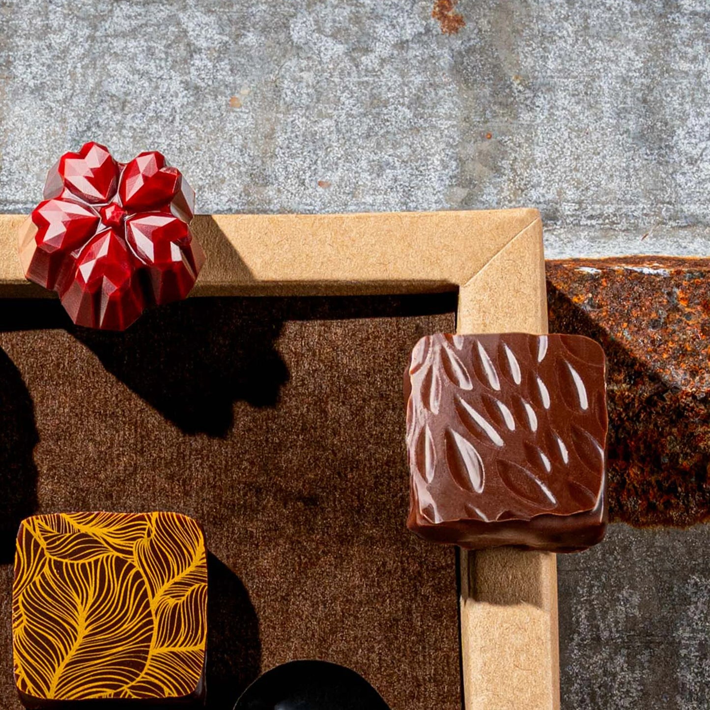 Chocolate bonbons with unique designs on a rustic metal surface