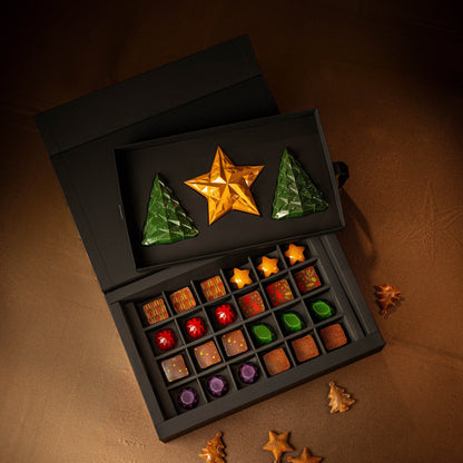 Assorted chocolates in a black box with decorative stars on a brown surface