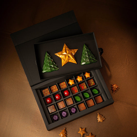 Assorted chocolates in a black box with decorative stars on a brown surface