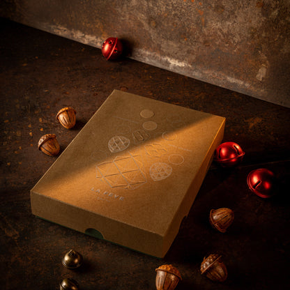 Wooden box with embossed design on a dark, textured surface with scattered nuts and red objects.