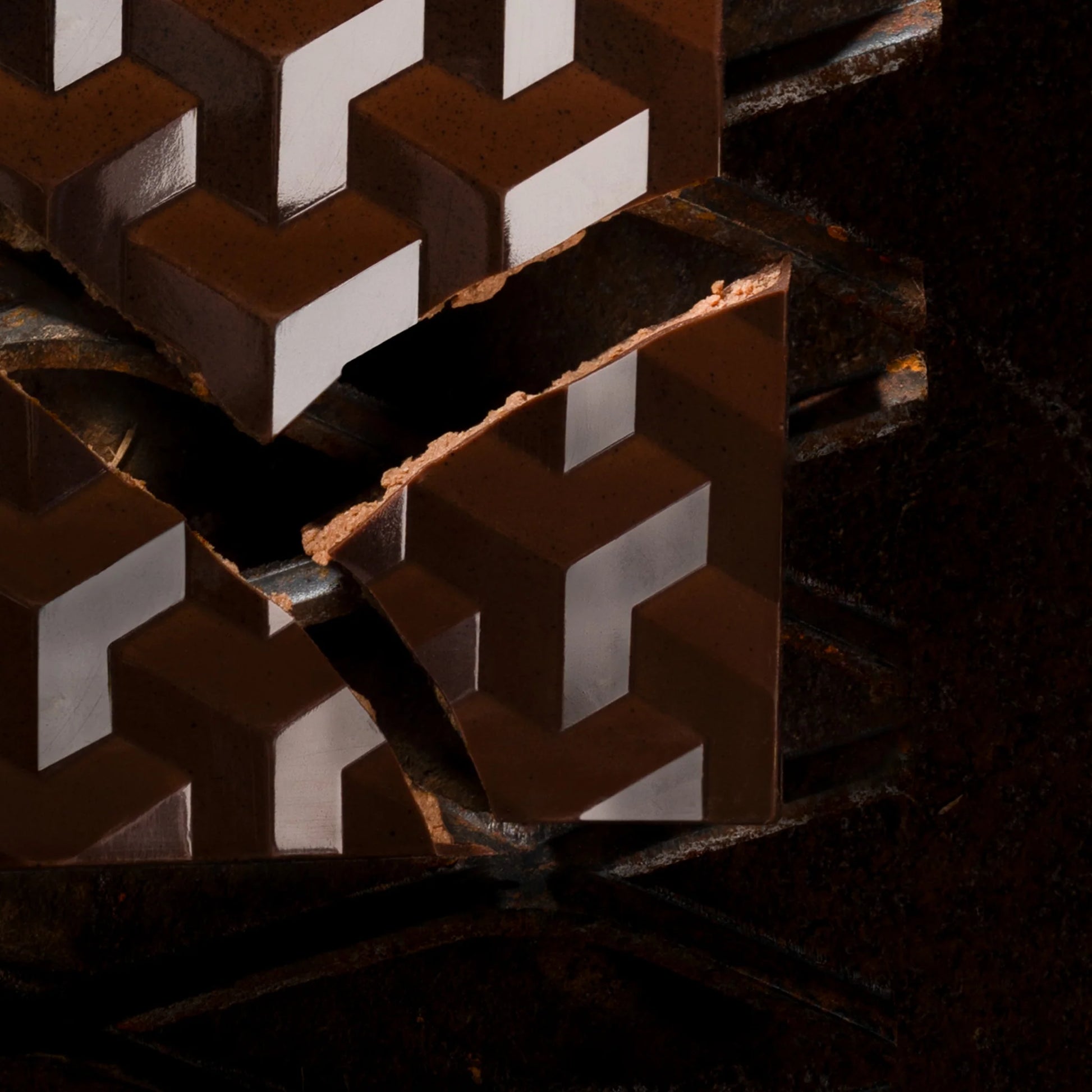 Close-up of a brown chocolate bar with geometric patterned onstructure with a dark background