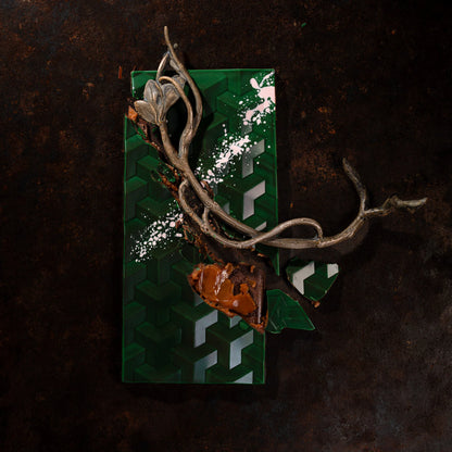 Decorative item with a green geometric pattern and metallic branch on a dark background