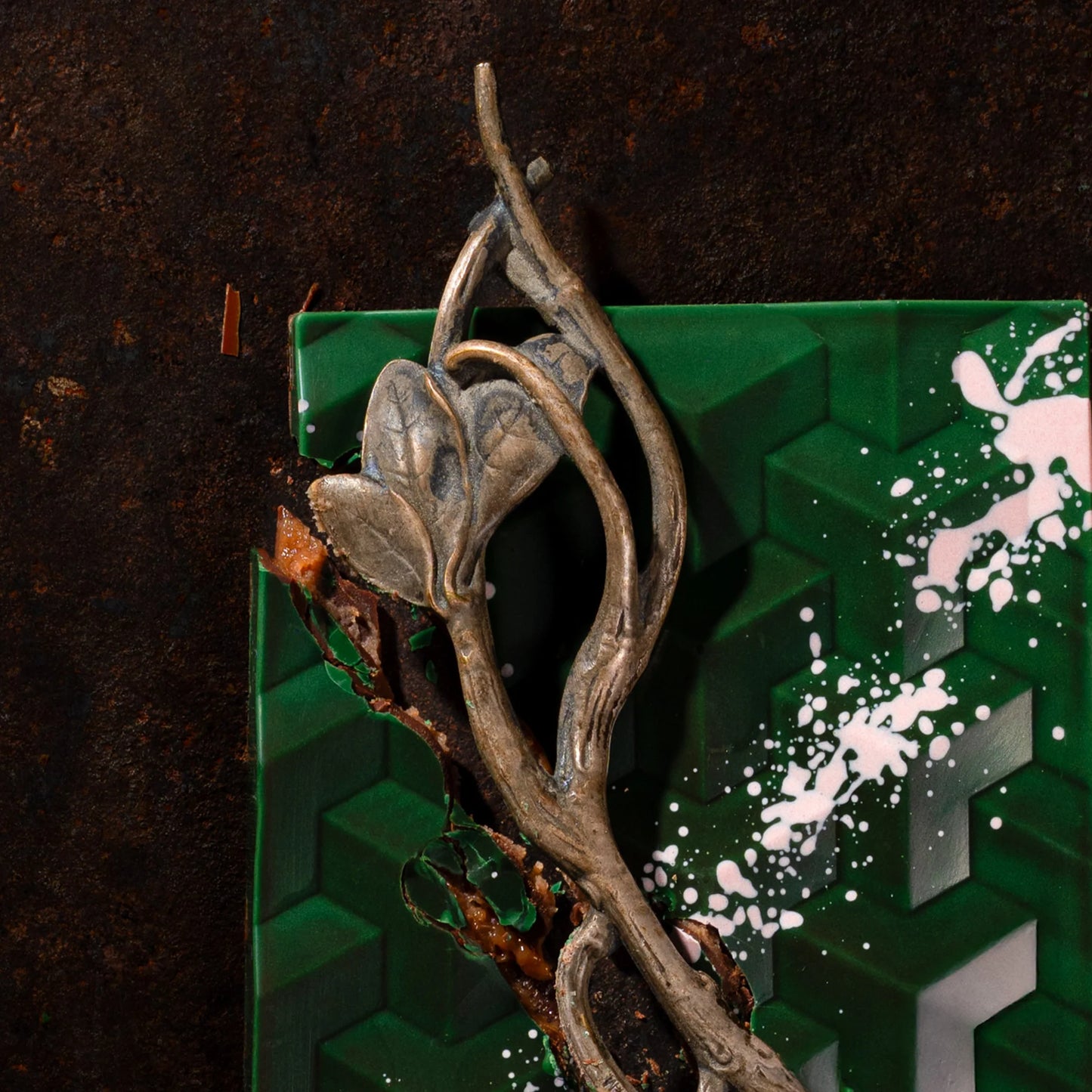 Decorative metal leaf design on a green chocolate bar and brown textured background